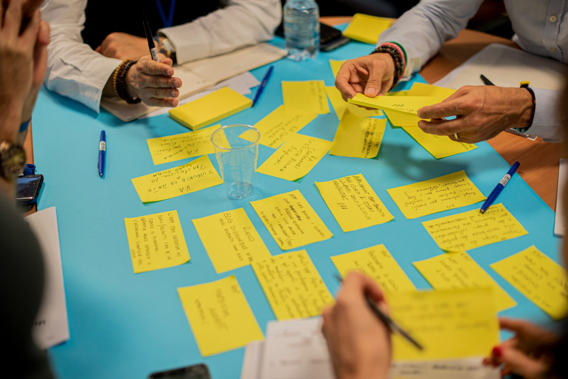 professionals gathered around a blue table sorting ideas written on yellow notecards