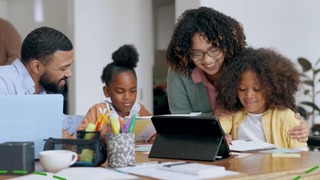 A man and a woman, with two young girls looking at and pointing to something on their computer screens.