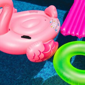 pink flamingo pool float, green round pool float in a pool