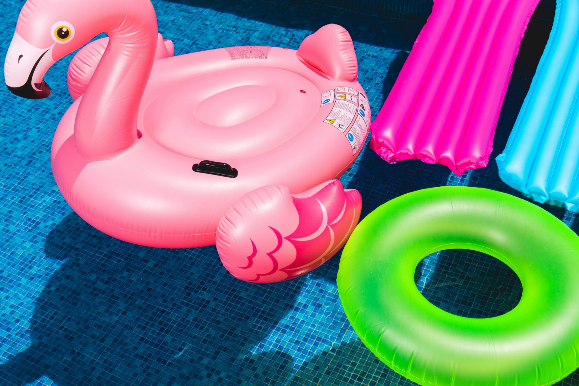 pink flamingo pool float, green round pool float in a pool