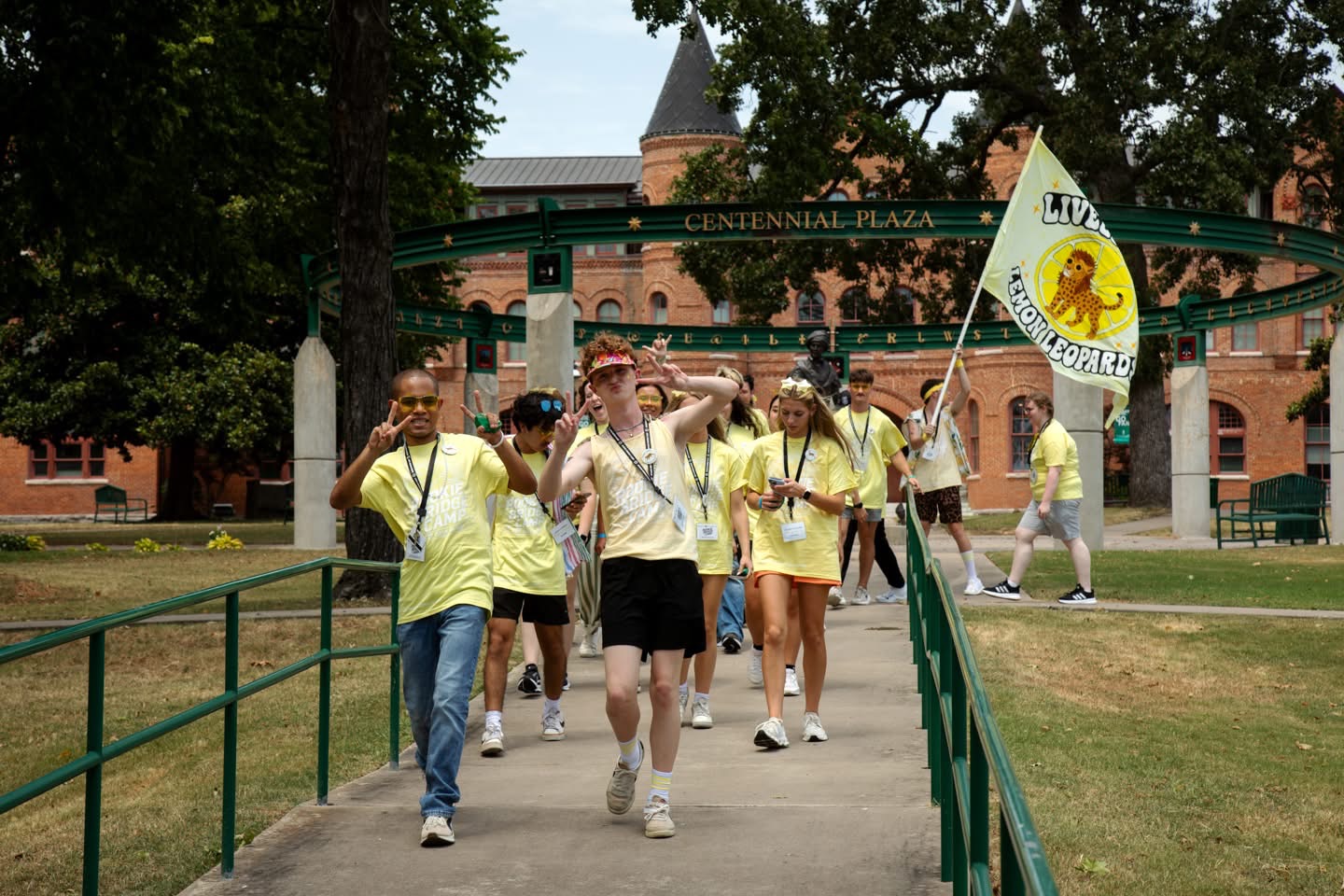 A group of students all wearing yellow shirts walk down a sidewalk at Northwestern State university